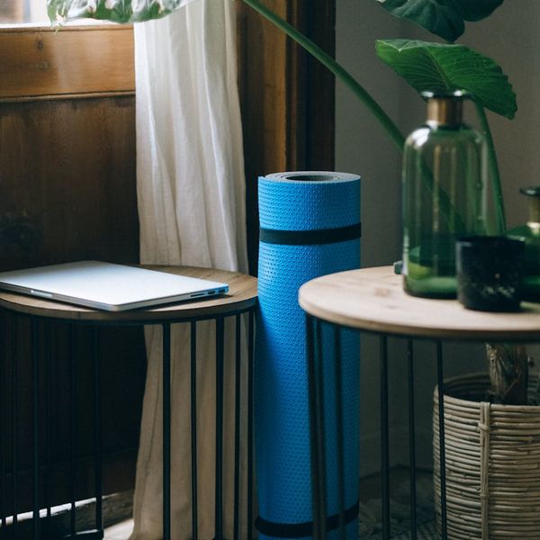 A cozy corner of a room with a yoga mat and a plant.