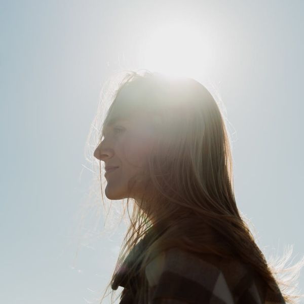 Person looking calm and content outdoors at sunrise.